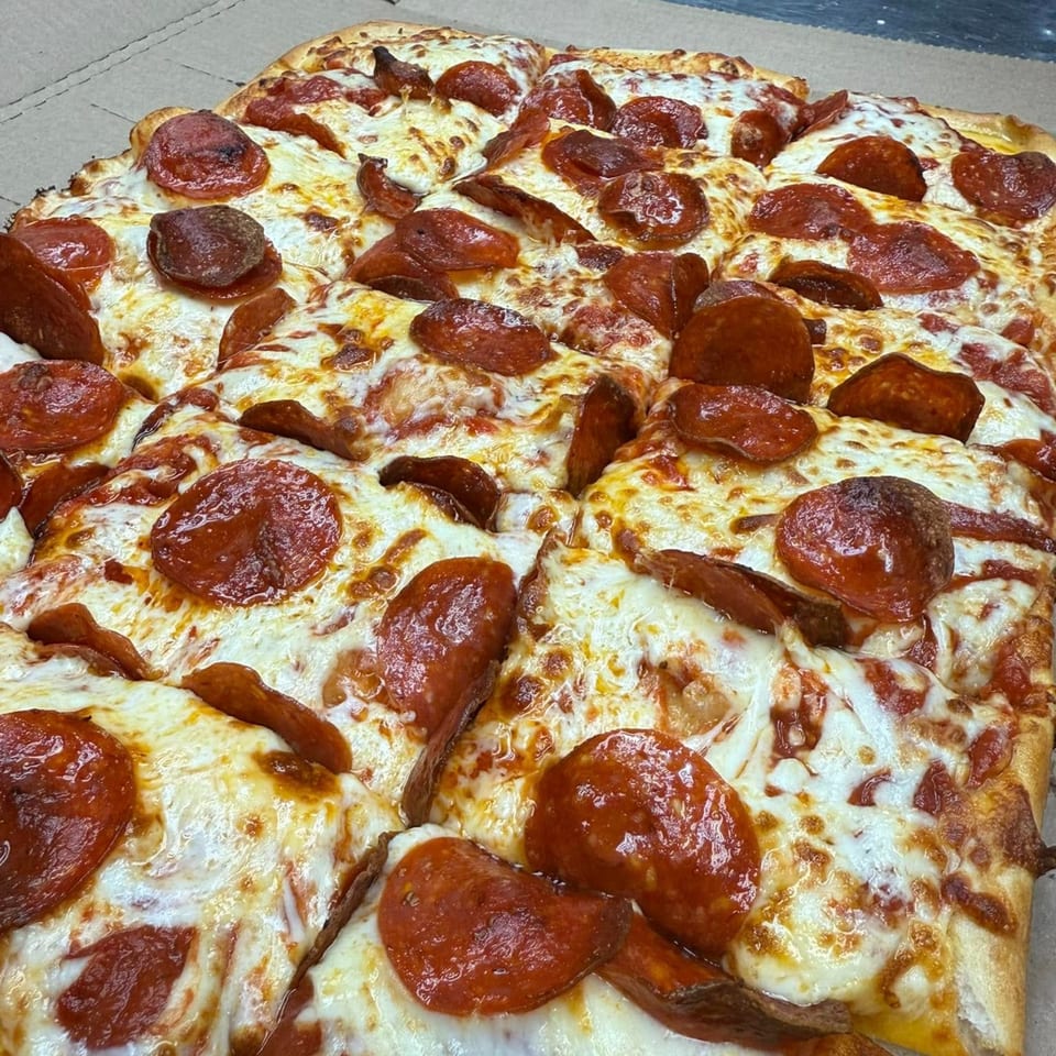 A large, rectangular Rego's Brickhouse Pizza pepperoni pizza, generously topped with cheese and pepperoni.