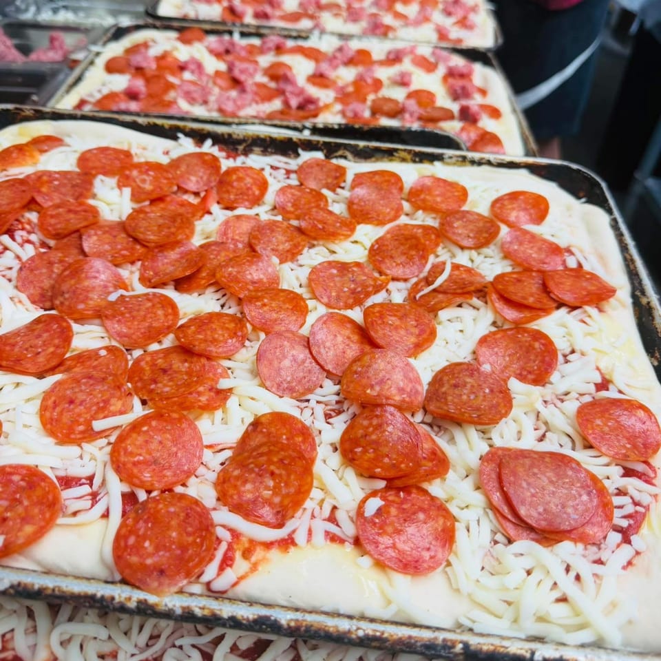 Multiple rectangular Rego's Brickhouse pizzas topped with pepperoni and shredded mozzarella cheese.
